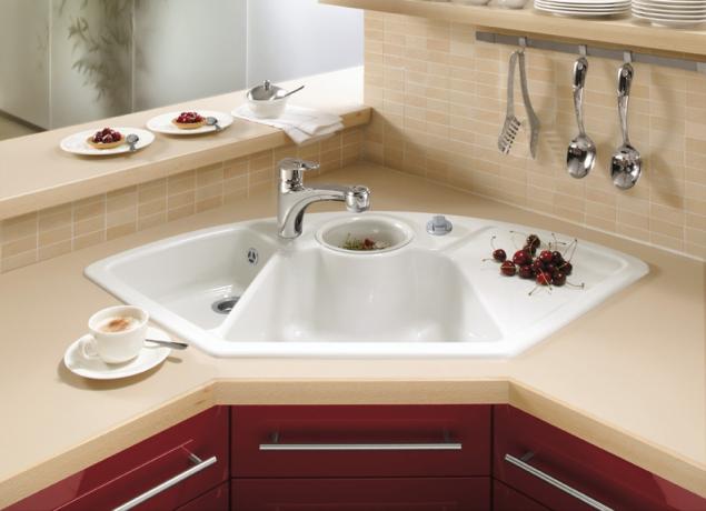 Billedet viser en hjørne køkkenvask med tre skåle og en dræn.